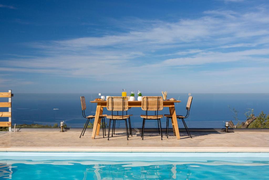 a wooden table and chairs next to a pool at Villa Alma in Kalamitsi