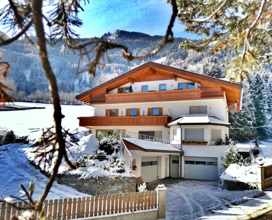 a house in the snow with a fence at Pramstaller Apartments in San Lorenzo di Sebato