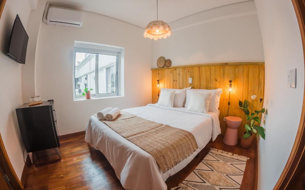 1 dormitorio con 1 cama grande y TV en Vilarejo - Centro Histórico Ilhabela, en Ilhabela