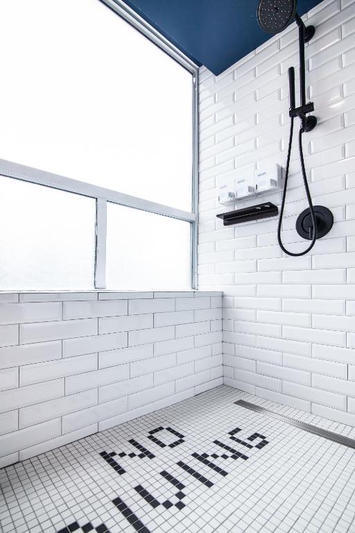 a white tiled bathroom with a sign that says new music at Hotel Belmont Vancouver - MGallery Collection in Vancouver