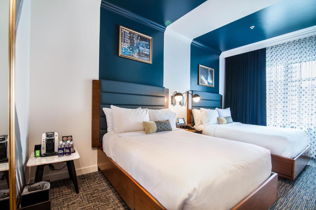 two beds in a hotel room with blue walls at Hotel Belmont Vancouver - MGallery Collection in Vancouver