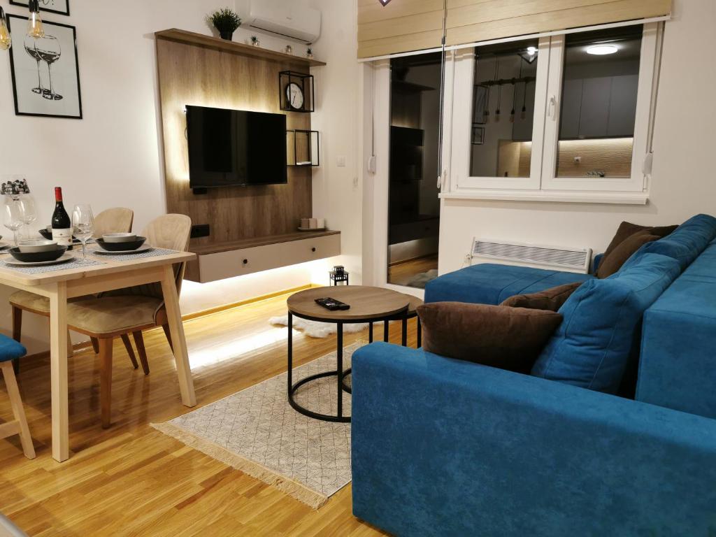 ein Wohnzimmer mit einem blauen Sofa und einem Tisch in der Unterkunft Apartman Maximus in Vrnjačka Banja