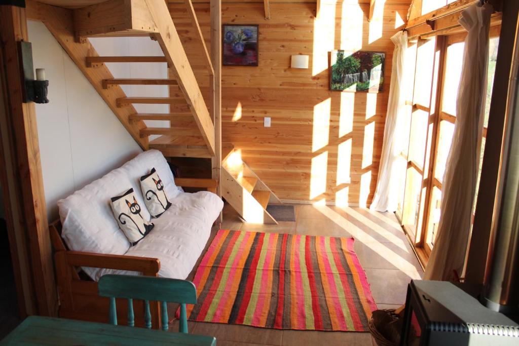 a living room with a couch and a staircase at Cabaña Los Carpinteros, Conguillïo, Sector Los Paraguas in Vilcún