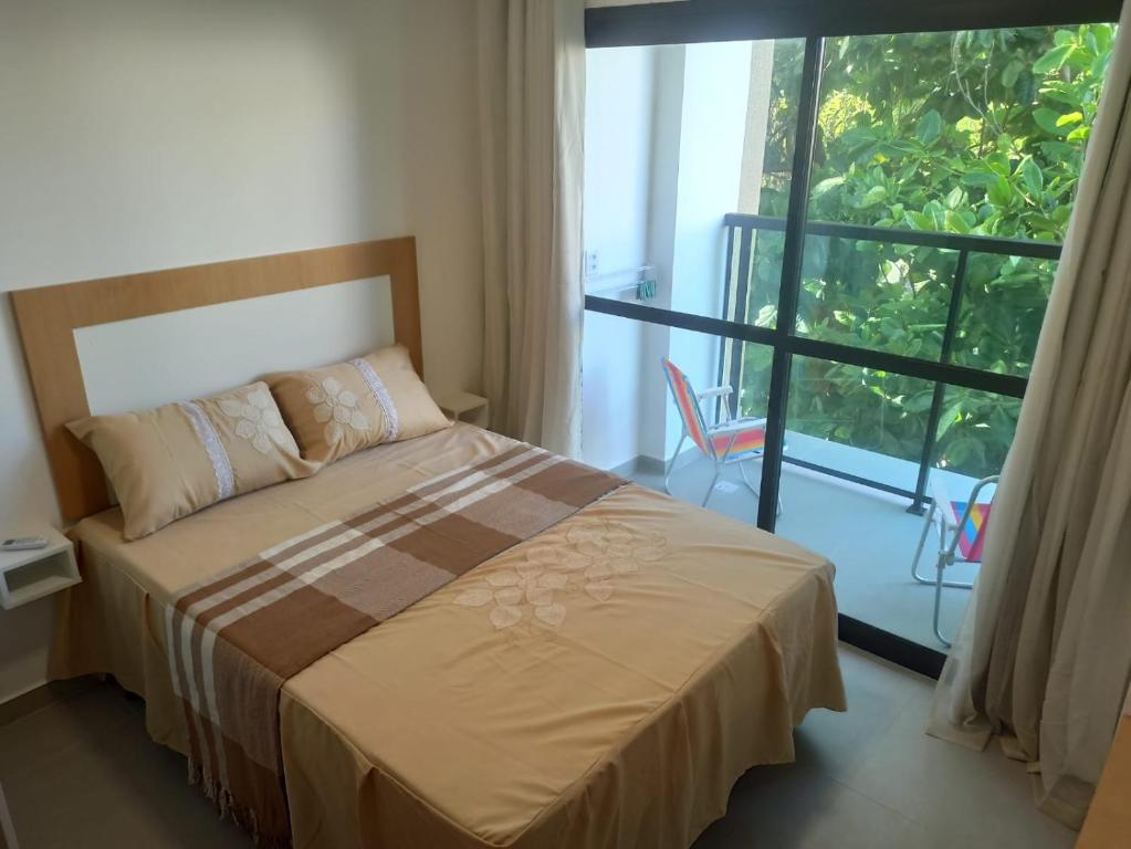 a bedroom with a bed and a large window at Flat Macaraípe - Maraca Beach I in Porto De Galinhas