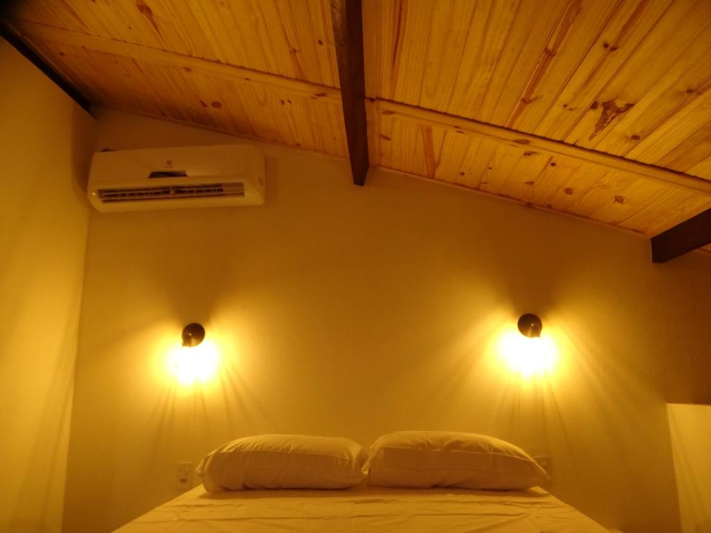 een slaapkamer met twee lampen aan de muur bij Cumbeba Tiny Houses in São Miguel do Gostoso
