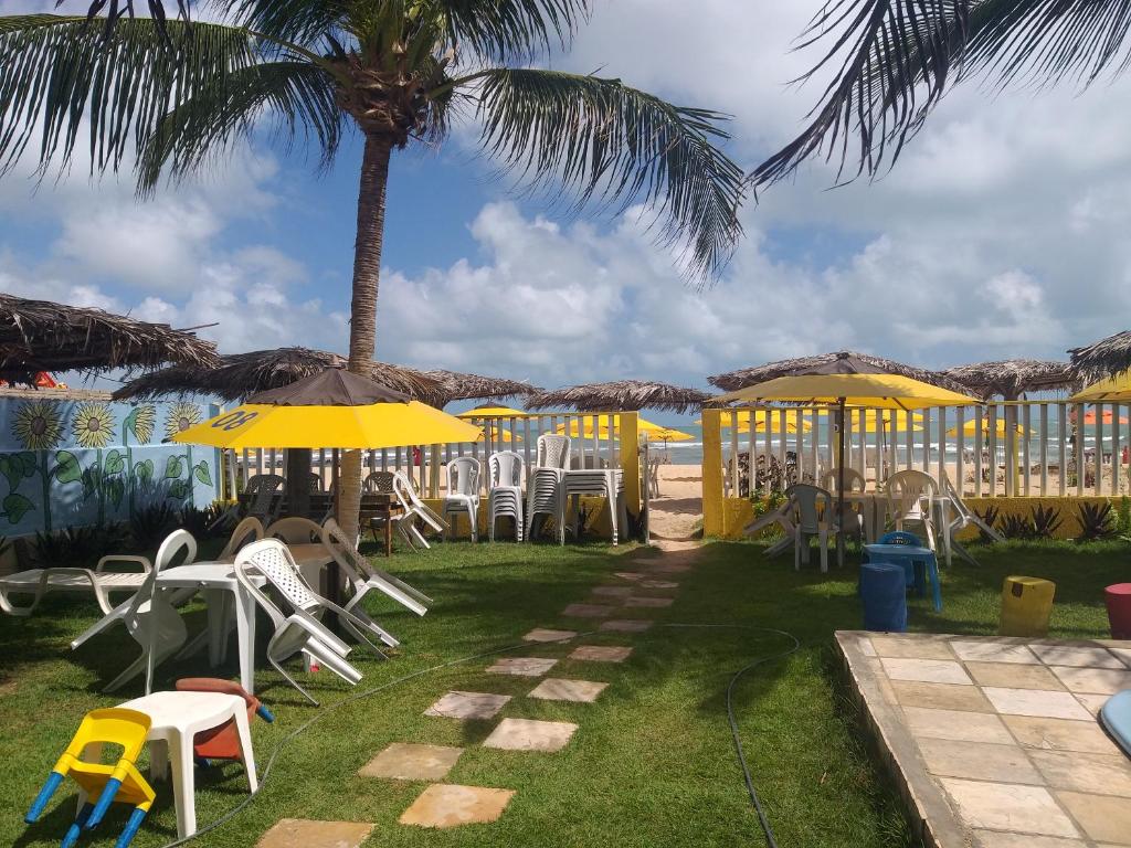 a group of chairs and umbrellas and a palm tree at Girassol Pousada in Extremóz