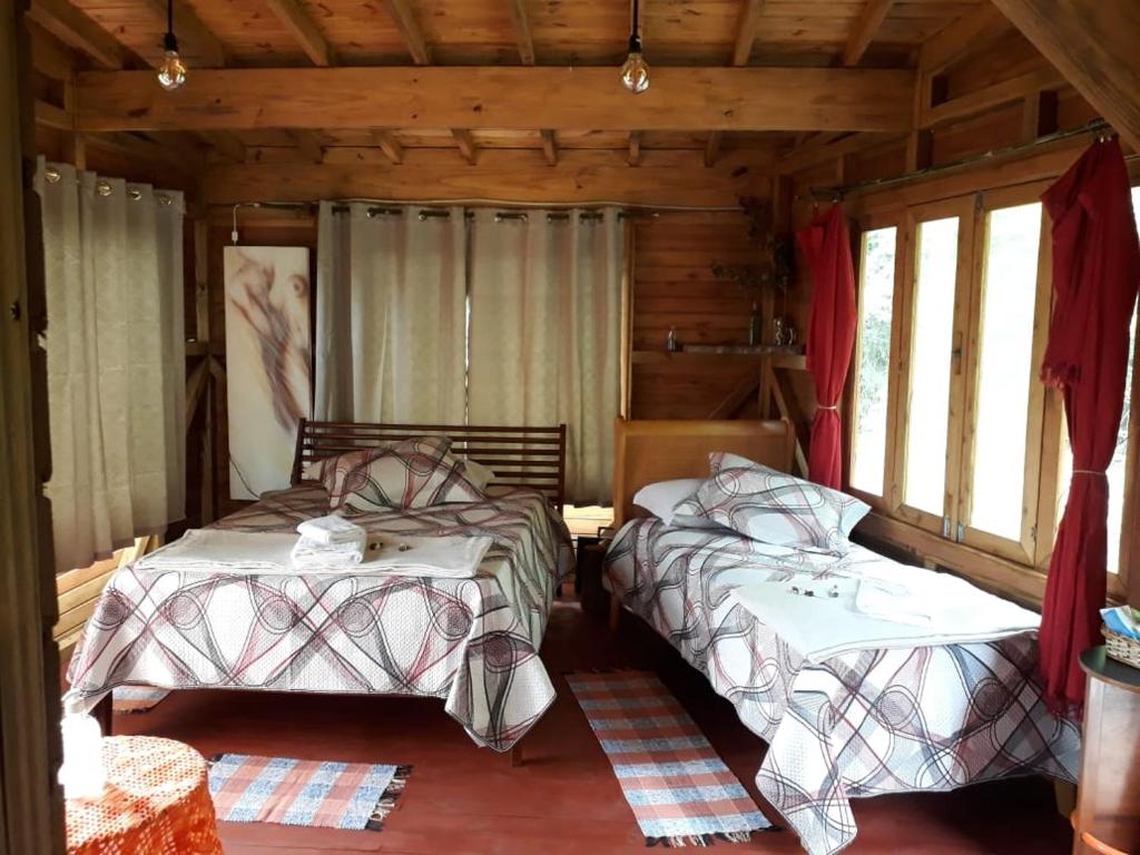 a bedroom with two beds in a log cabin at Eco Aldeia in Nova Petrópolis
