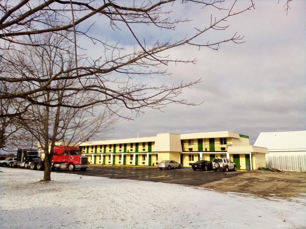 a building with cars parked in a parking lot at Granada Inn Motel - Kalkaska in Kalkaska