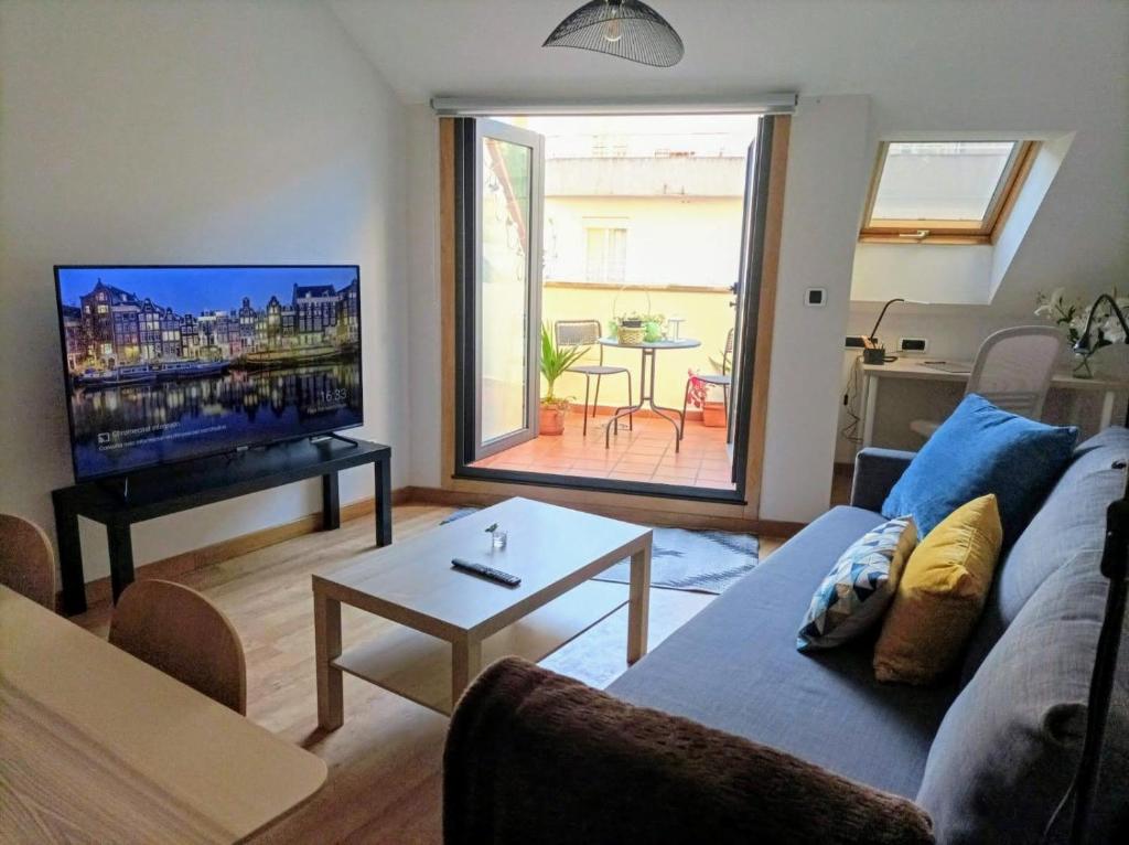 ein Wohnzimmer mit einem Sofa und einem Flachbild-TV in der Unterkunft Apartamento con Terraza, Plaza América in Vigo