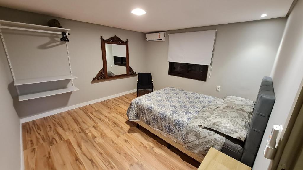 Schlafzimmer mit einem Bett und einem Spiegel in der Unterkunft NEO CASA in Gramado