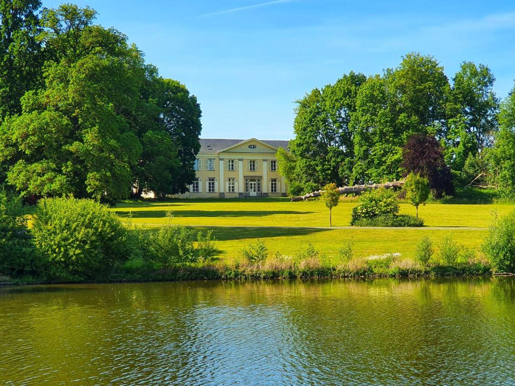 een groot huis met een vijver ervoor bij B&B T'Rest - Park ter Rijst in Heikruis