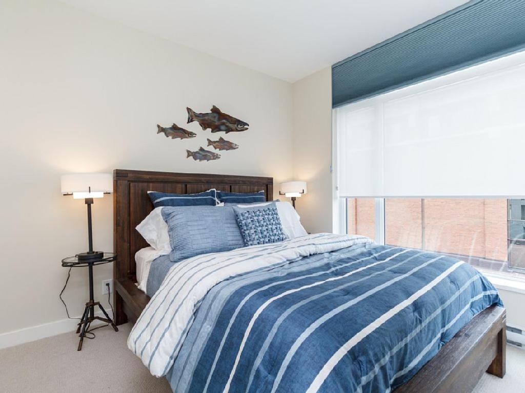 Un dormitorio con una cama azul y blanca y una ventana en Sparkling Gem, Brand New Condo In The Heart Of The City en Victoria