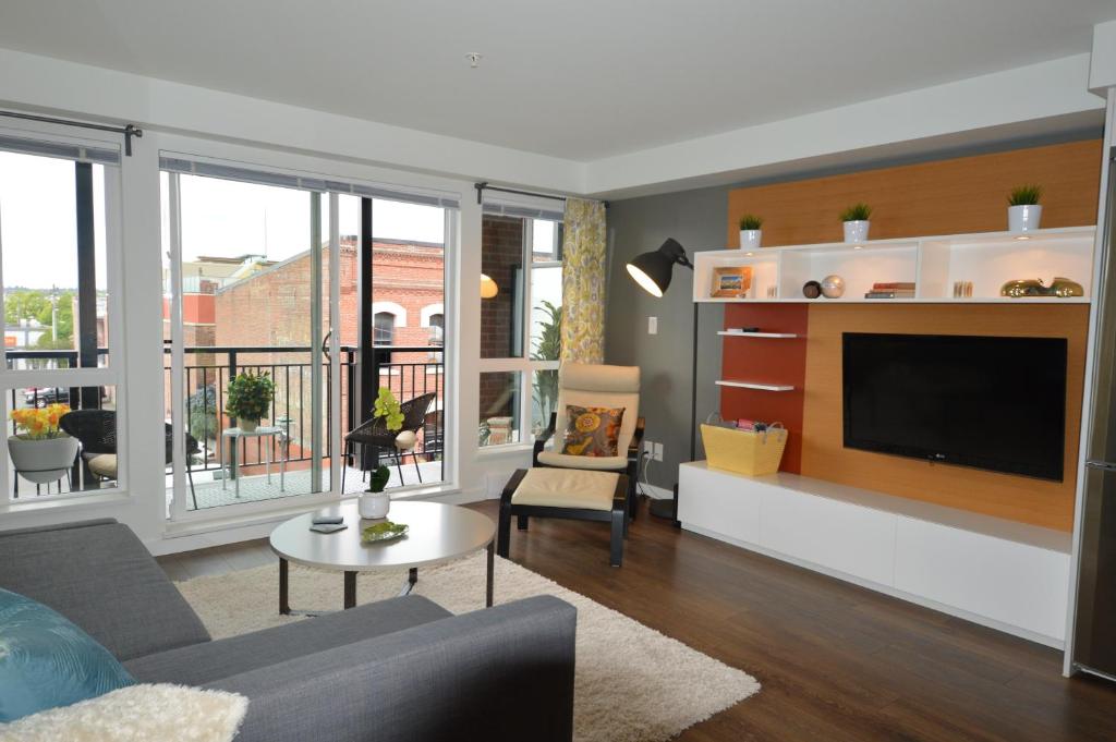 a living room with a couch and a tv at Chic 1Br Steps From Chinatown And Harbour in Victoria