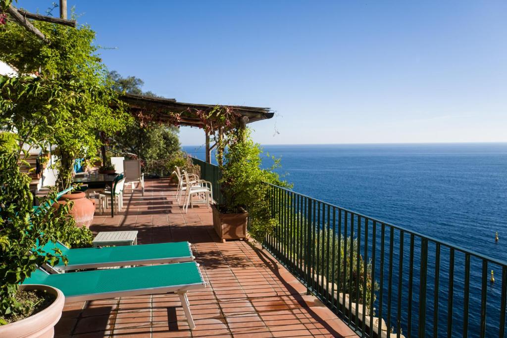 a balcony with green benches and the ocean at Luxury villa, pool, sea access, large terraces, stupendous views in Furore