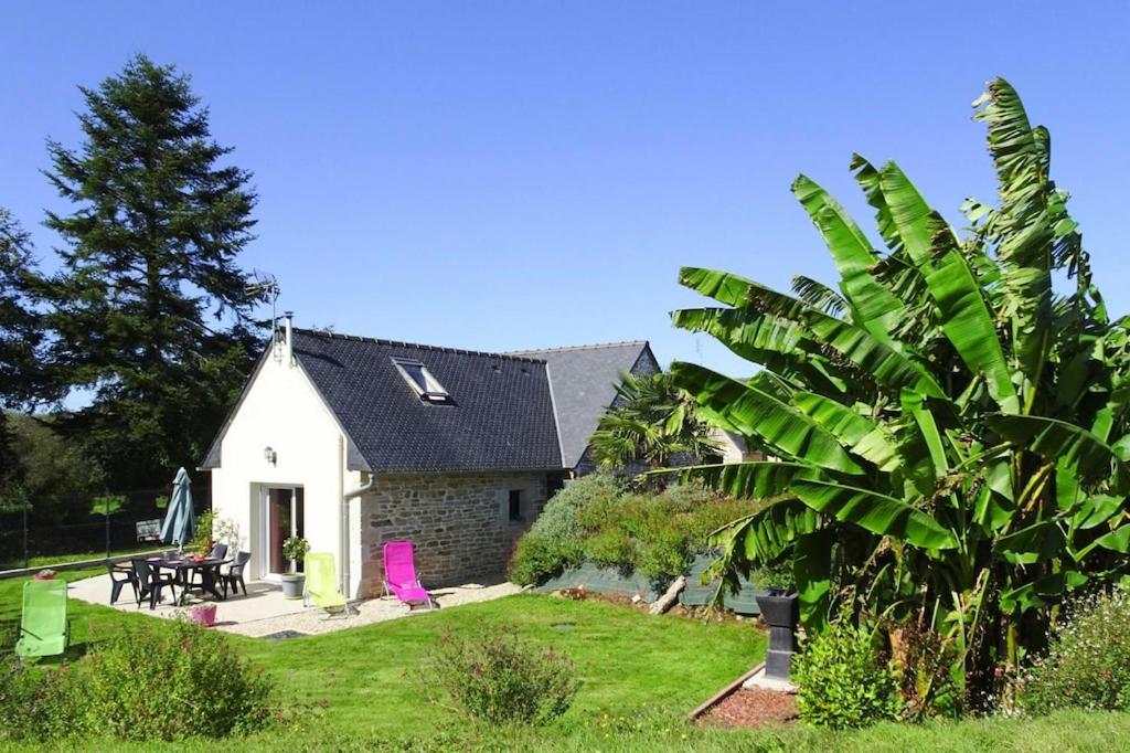 a white house with a palm tree in front of it at Cottage, Guerlesquin in Guerlesquin