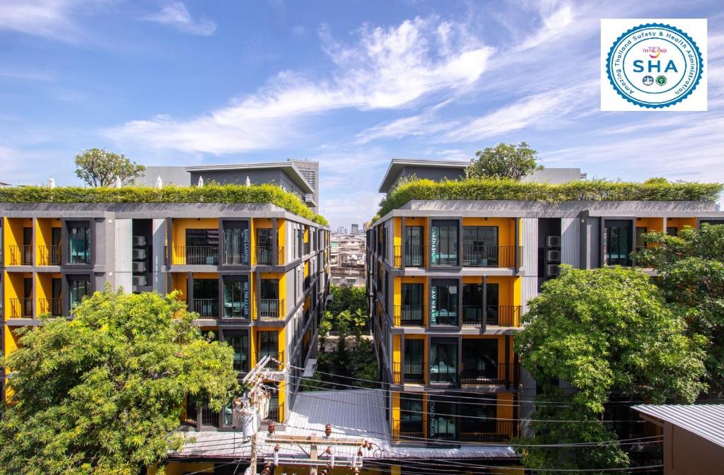 バンコクにあるアイサヌック バンコクの植物のある二棟のアパートのイメージ