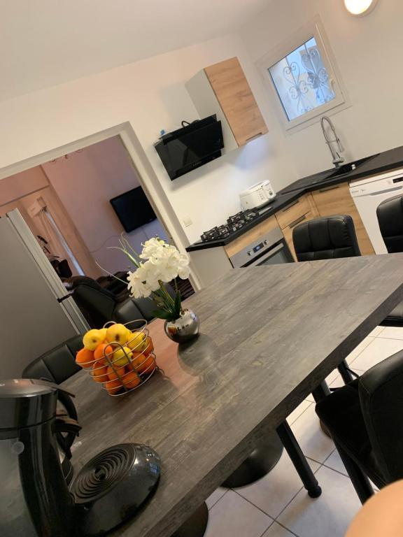 - une table en bois avec un vase de fruits dans l'établissement Maison entière avec terrasse barbecue et jardin, à Nîmes