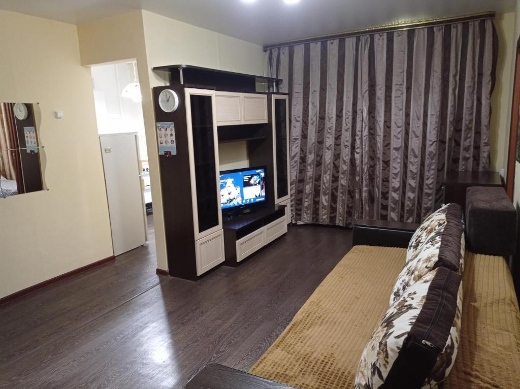 uma sala de estar com uma televisão de ecrã plano e um sofá em 2к. Апартаменты НСК,на ул. Блюхера 6 em Novosibirsk