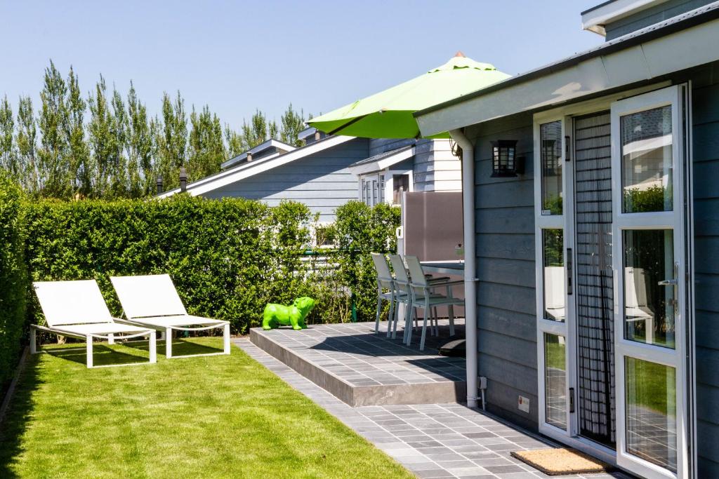 a patio with two chairs and a table in a yard at luxe cottage knokke heist in Knokke-Heist