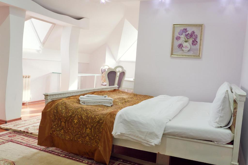 ein weißes Schlafzimmer mit einem Bett und einem Stuhl in der Unterkunft Hotel EZIO in Chişinău