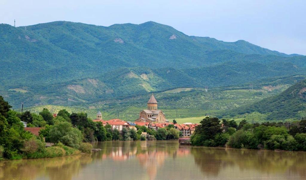 a building on the side of a river with mountains at Levanto in Mtskheta