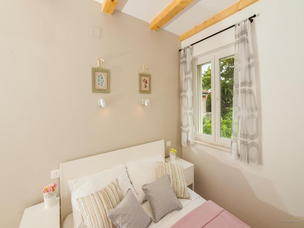 a white bedroom with a bed and a window at Aldo Apartments Center in Zadar