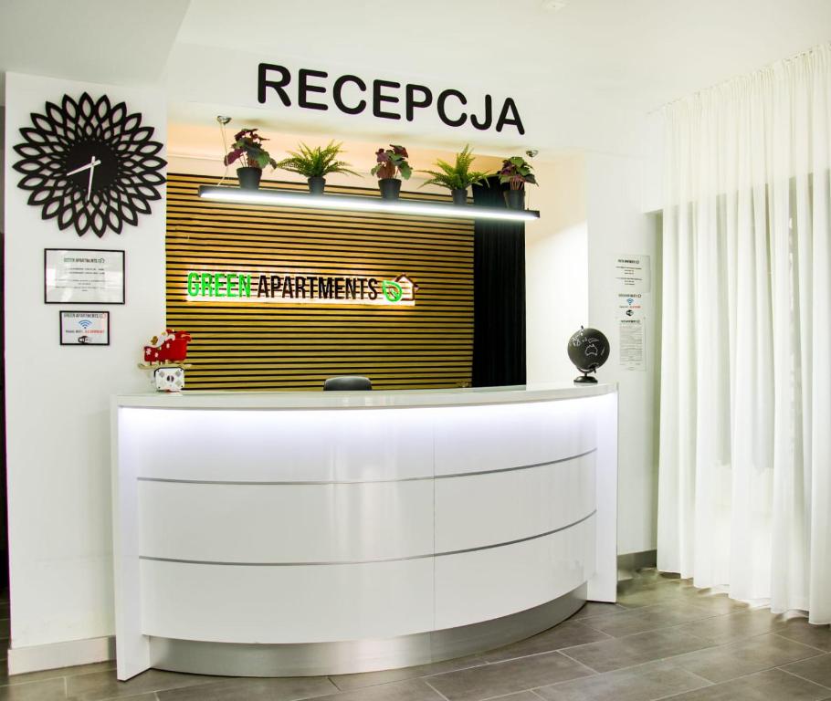 a reception desk with a sign on a wall at Green Apartments Katowice Chorzów in Chorzów