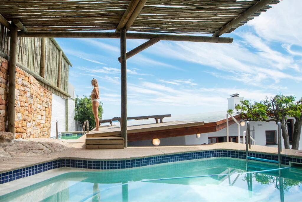 a woman is standing next to a swimming pool at Bantry Bay Home with Atlantic Ocean Views in Cape Town