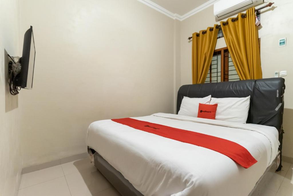 Schlafzimmer mit einem großen weißen Bett mit roten Akzenten in der Unterkunft RedDoorz At Joyce Guest House Medan in Medan