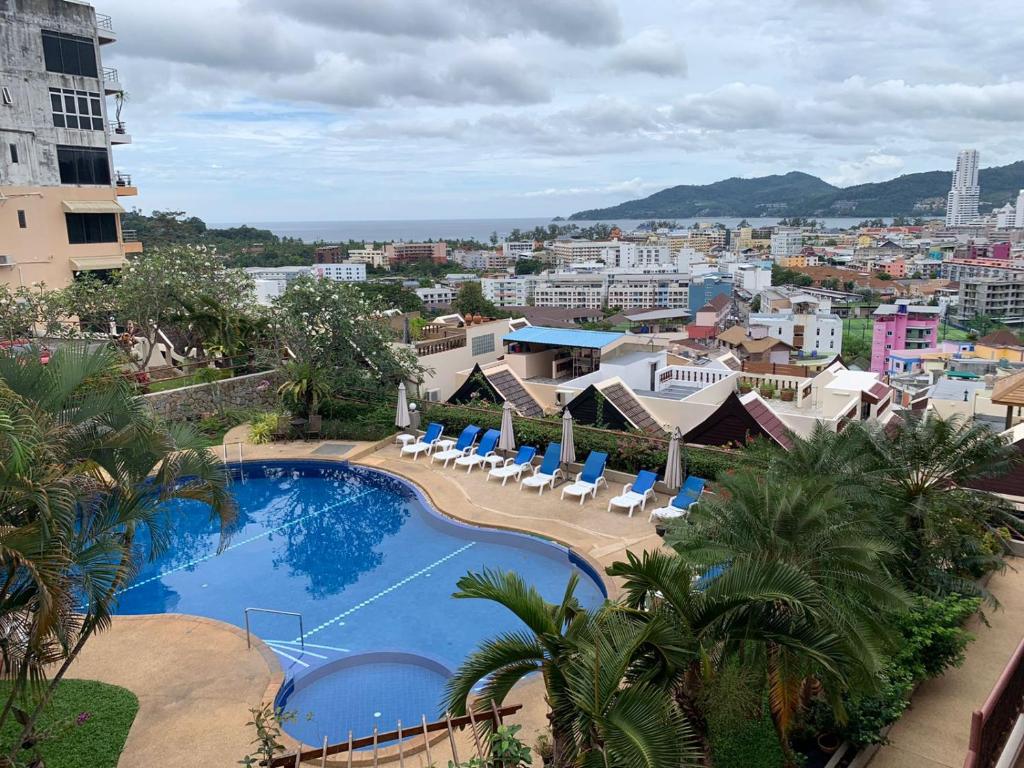 a view of a swimming pool with chairs and a city at Beverly Hills Villa Patong in Patong Beach