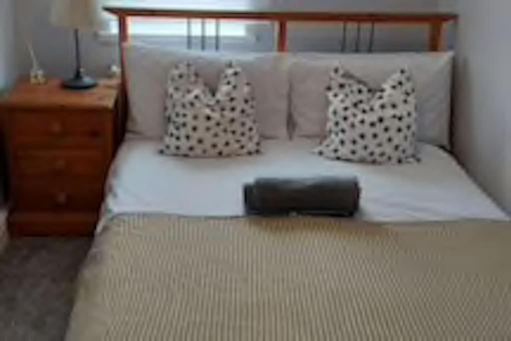 Cama con cabecero de madera y almohadas en White Shelf West Dartford, en Kent