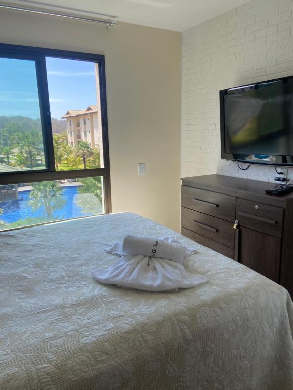 a bedroom with a bed with a tv and a large window at Vg Sun cumbuco 310 c4 in Cumbuco