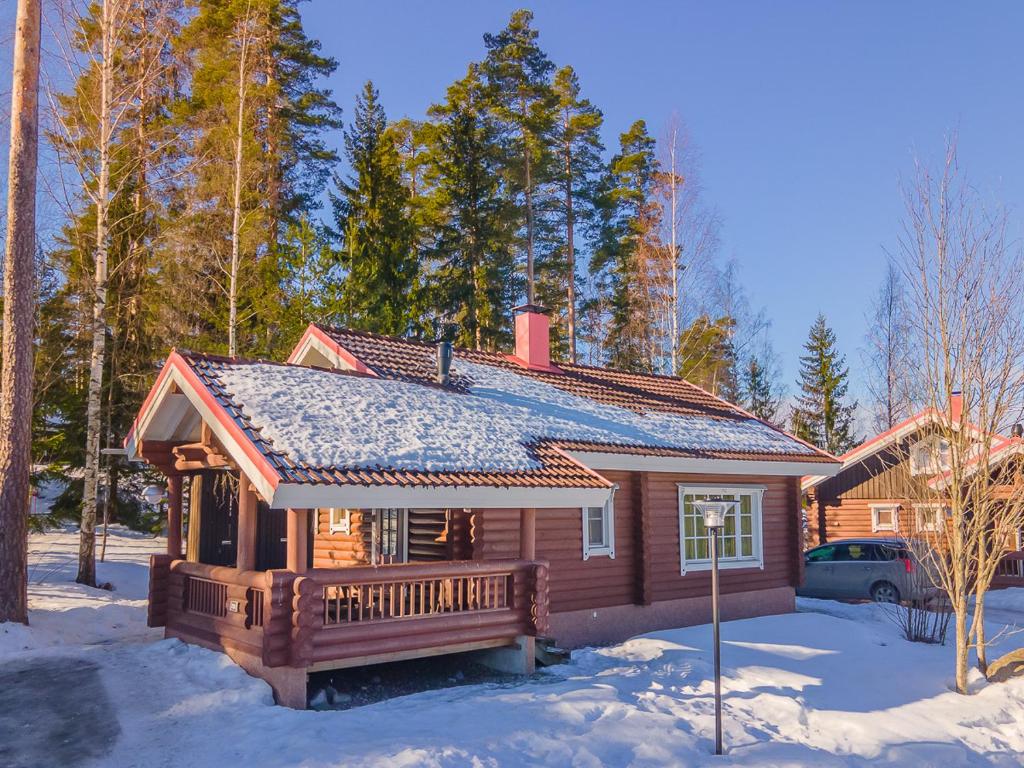 uma cabana de madeira com um alpendre na neve em Villa Kurpitsa at MESSILA ski & camping em Hollola
