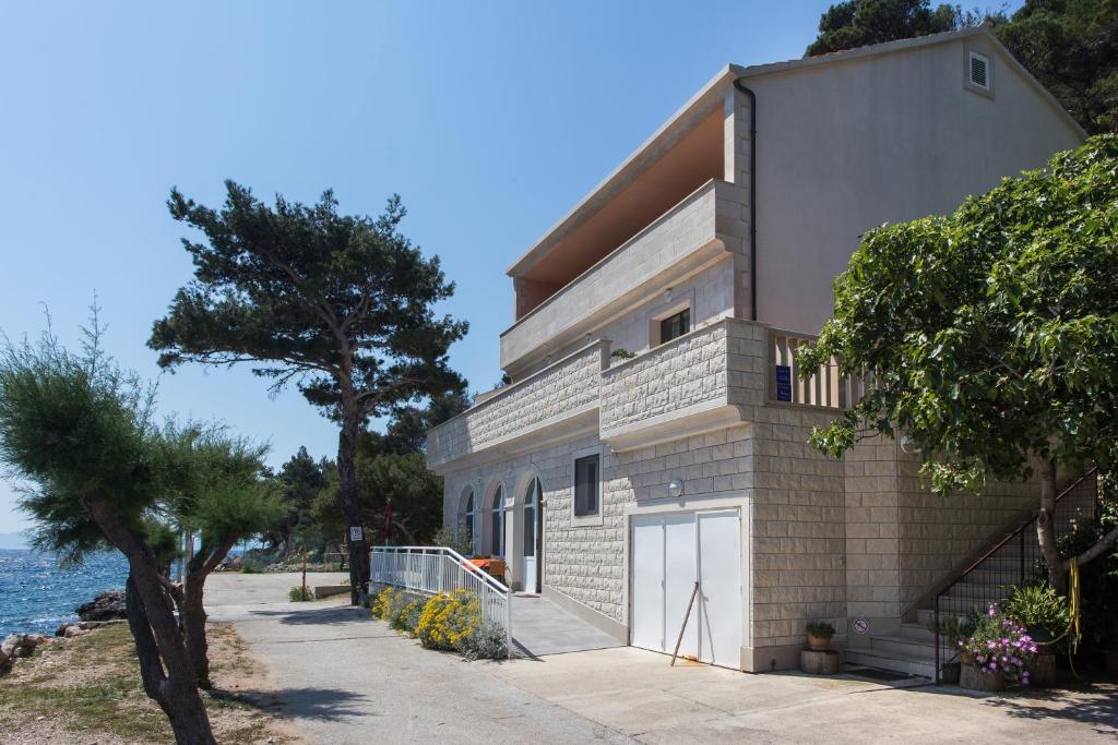 un bâtiment à côté de l'eau avec un arbre dans l'établissement Apartments Bezek, à Trstenik