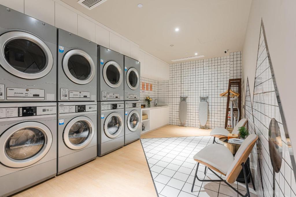 a laundry room with multiple washing machines and a chair at Atour Hotel Nanjing Xianlin Center Jinying Plaza in Nanjing
