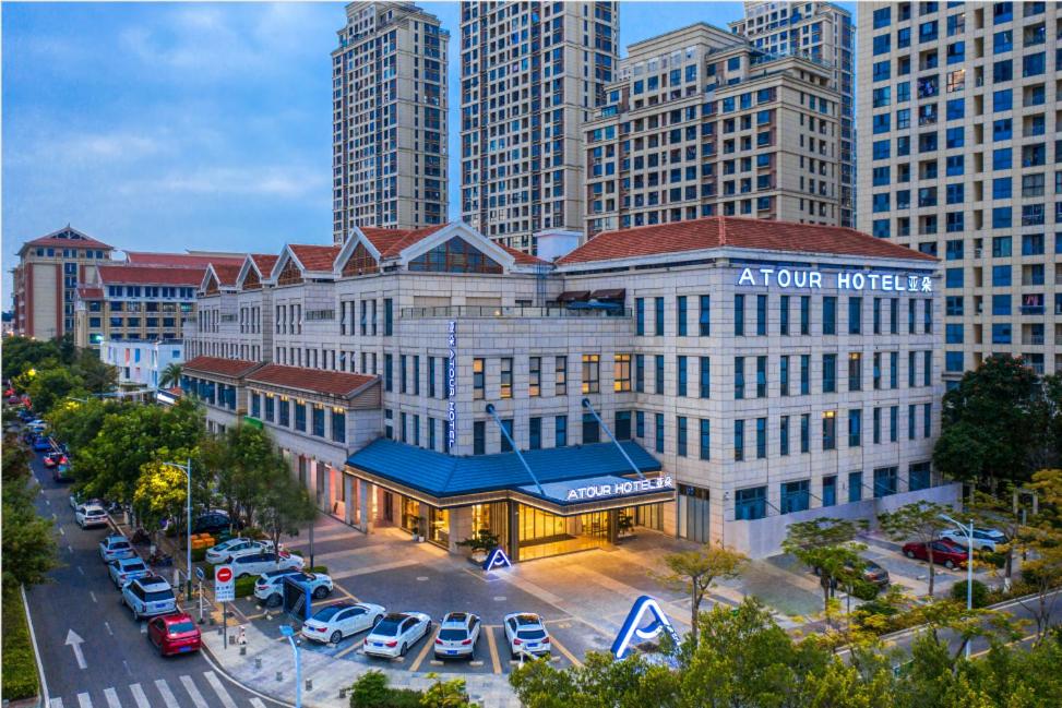 a hotel in a city with cars parked in a parking lot at Atour Hotel Xiamen Jimei Lake Business Center in Xiamen