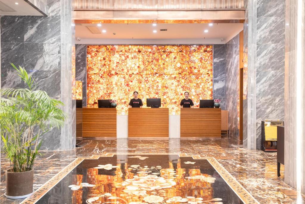 um lobby com duas pessoas sentadas na recepção em Atour X Hotel Yancheng Lingxiang Xinlong Road em Yancheng