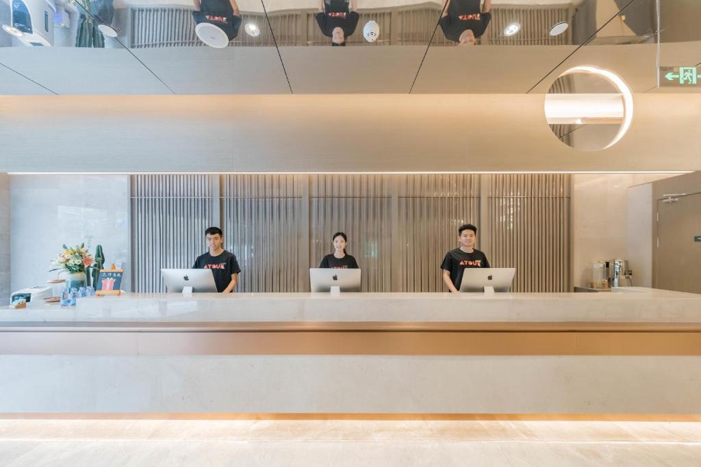 three people sitting at a counter with their laptops at Atour Hotel Hangzhou East Railway Station in Hangzhou