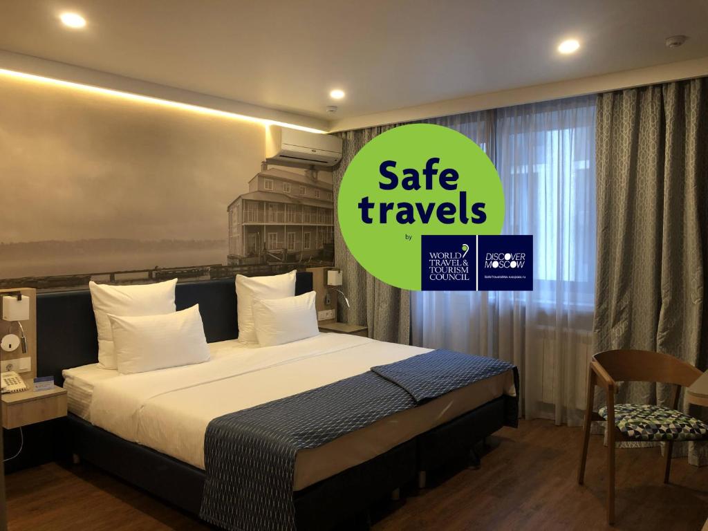 a bedroom with a bed and a sign that reads safe travels at Volga Apart Hotel in Moscow