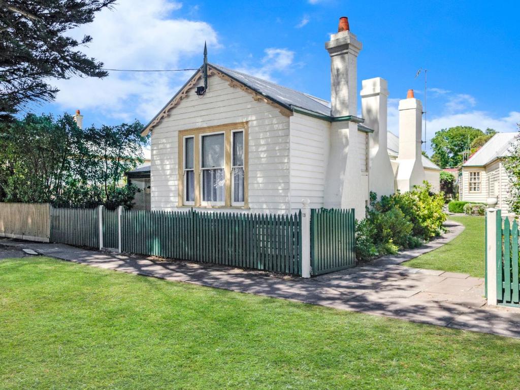 una casa bianca con una recinzione verde di Lavender Cottage a Port Fairy