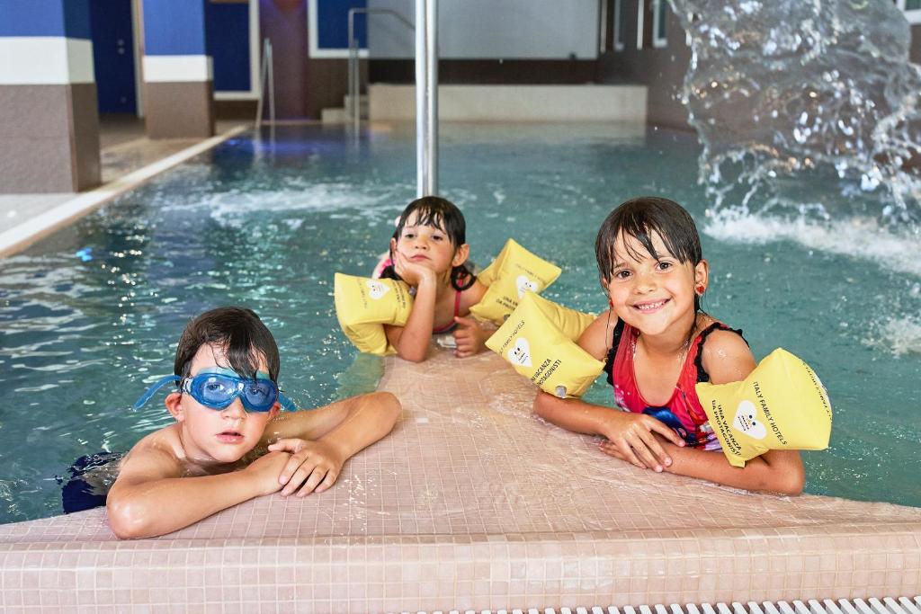 3 bambini sdraiati in una piscina di Family Hotel Andes - Only for Family a Vigo di Fassa