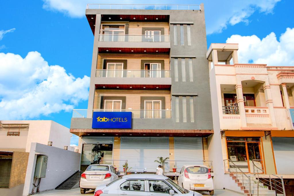 un edificio con auto parcheggiate di fronte di FabHotel 7th Crossing a Jaipur