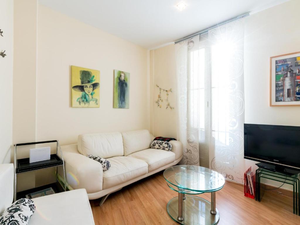 sala de estar con sofá blanco y TV en Holi-Rent Goya en Sevilla