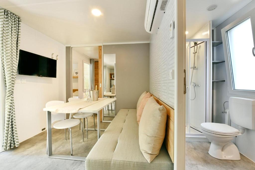 a small bathroom with a bench in front of a toilet and a sink at Polidor Camping Resort in Poreč