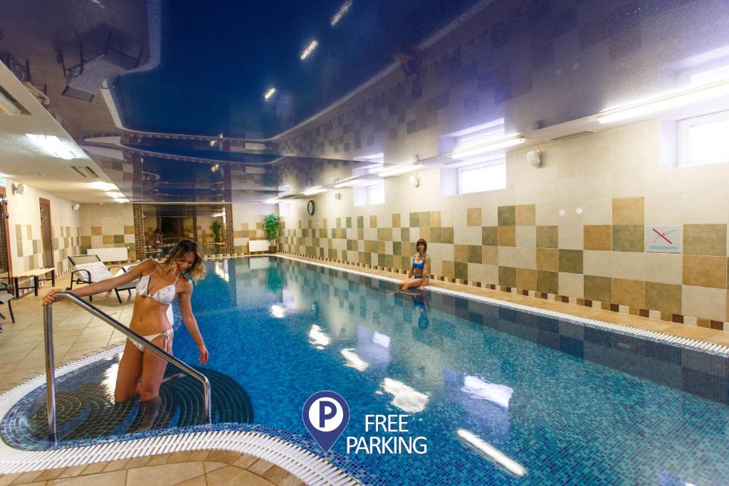 a woman is standing next to a swimming pool at Hotel Rocca al Mare in Tallinn