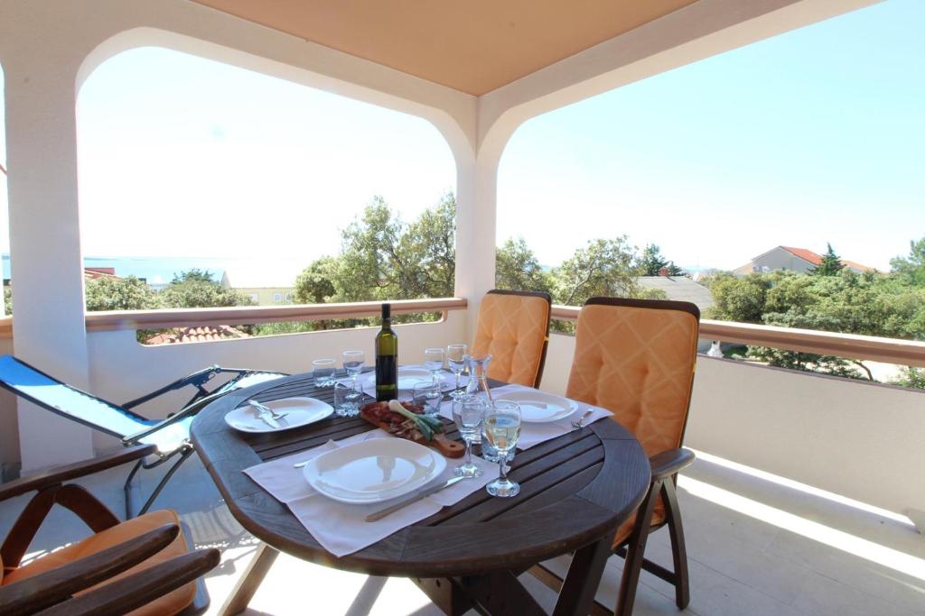 stół z butelką wina i kieliszkami na balkonie w obiekcie Apartments Karas on the island of Pag w mieście Mandre
