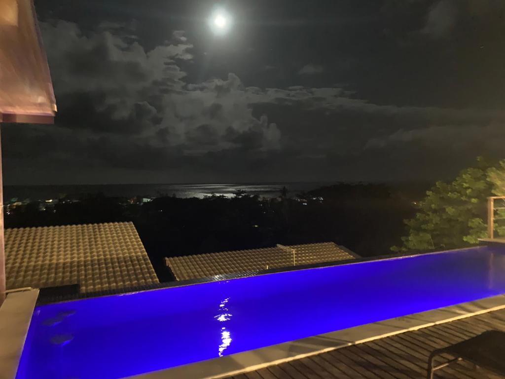 a swimming pool at night with the moon in the sky at TRANQUILA FLATS in Morro de São Paulo