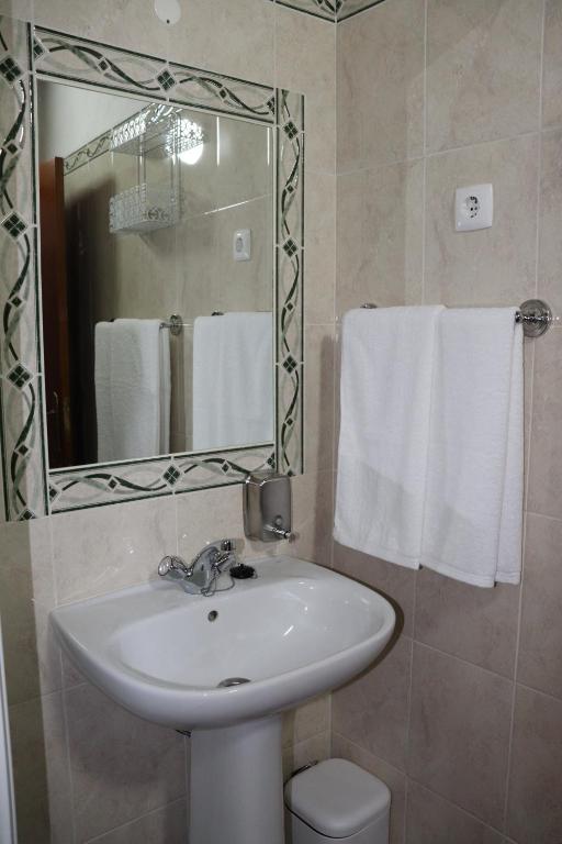 W łazience znajduje się umywalka, lustro i ręczniki. w obiekcie Casa do Celeiro - Monsaraz w mieście Monsaraz
