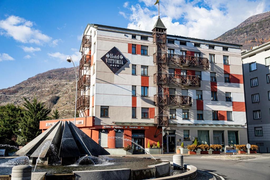 a hotel with a fountain in front of a building at Hotel Vittoria in Sondrio