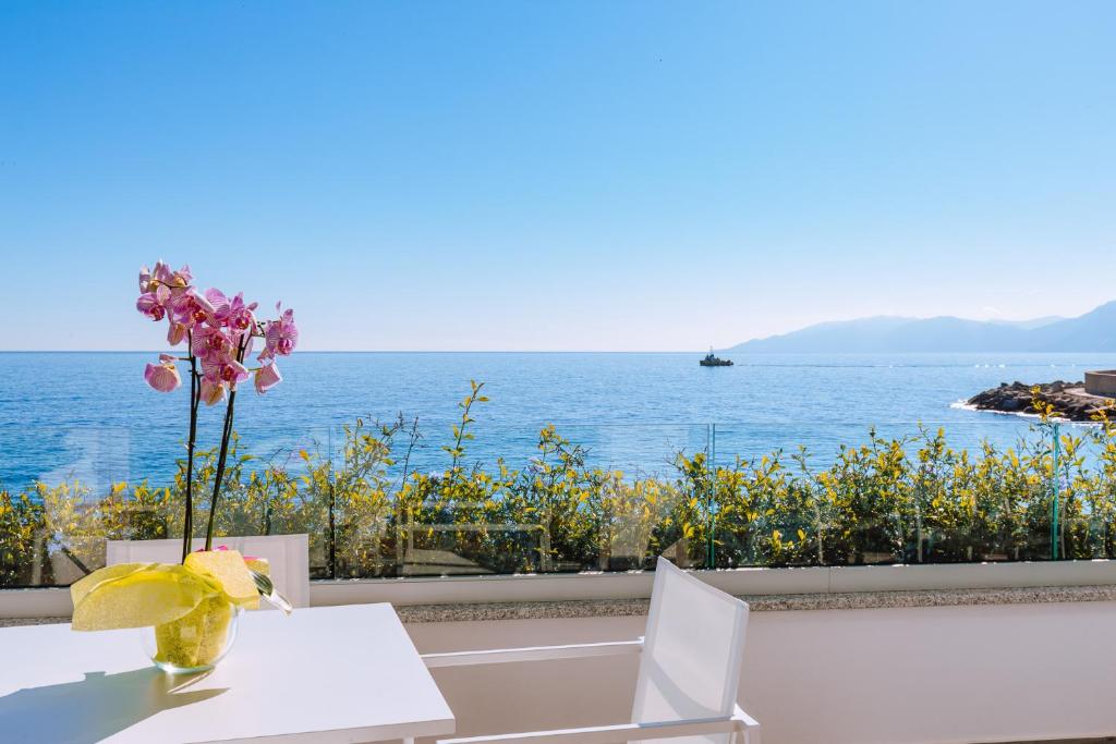 una mesa con un jarrón de flores sobre el océano en Hotel Caramare, en Cala Gonone
